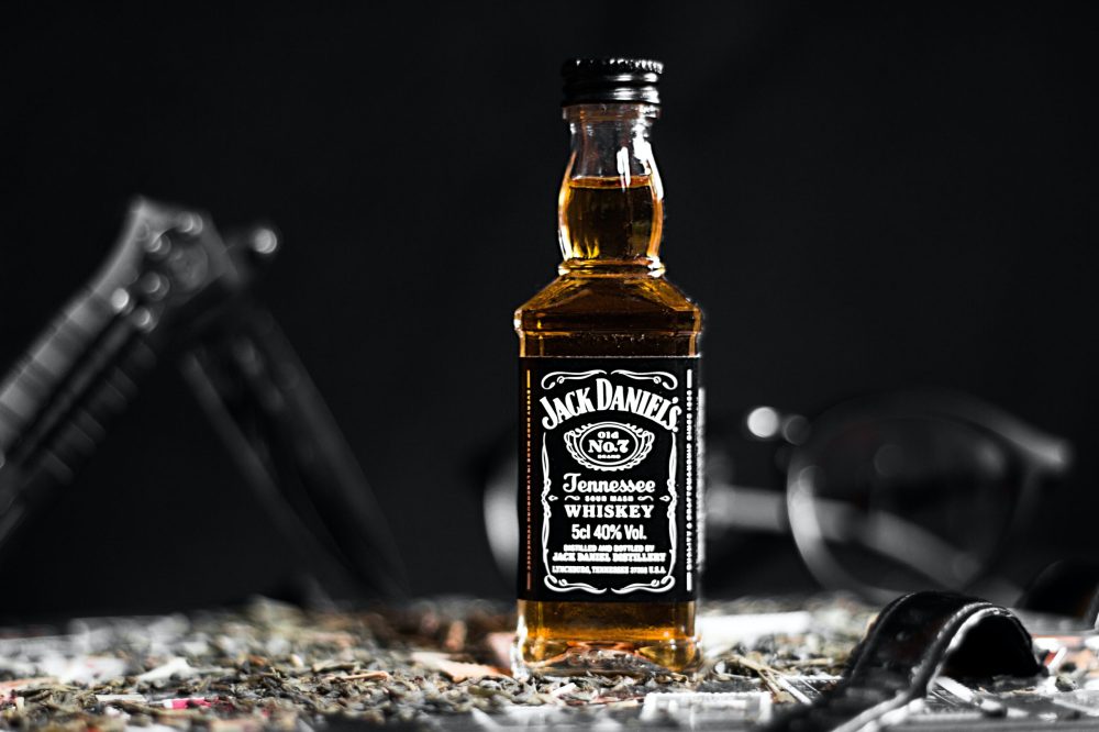 a close up of a bottle and a glass of wine with Jack Daniel's in the background