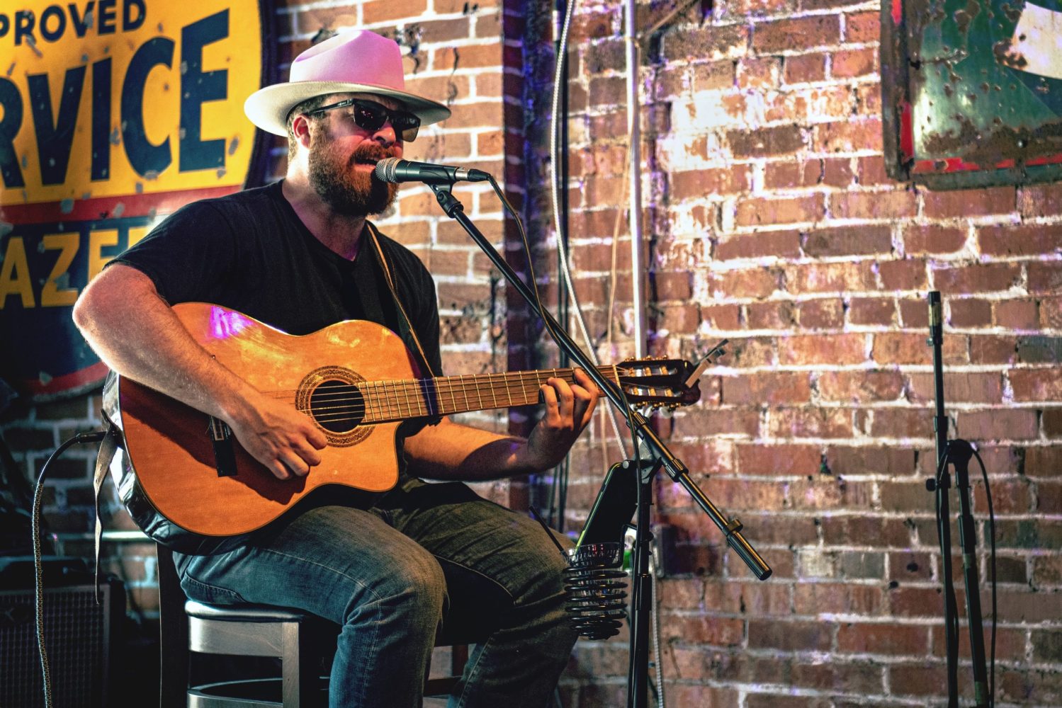 a man holding a guitar in front of a brick wall